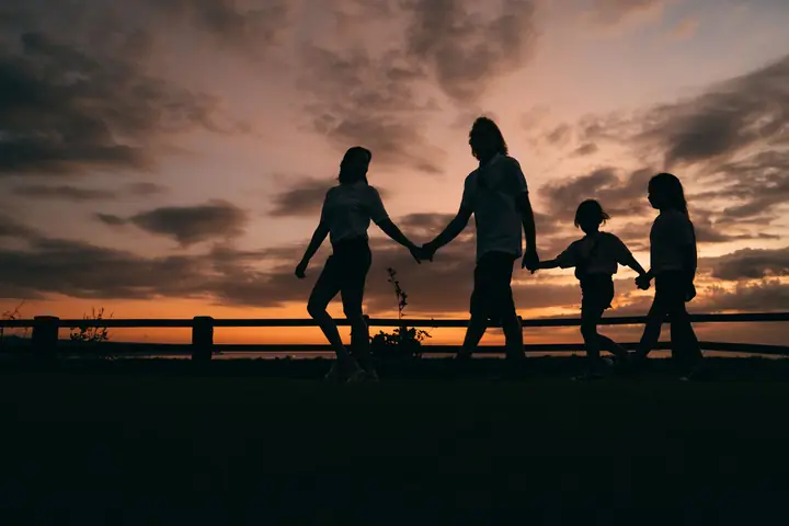 Une famille main dans la main au coucher du soleil