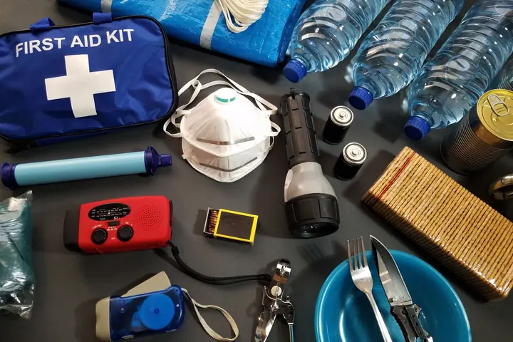 Le matériel d'un kit d'urgence posé sur une table : eau, lampe, radio, trousse de secours